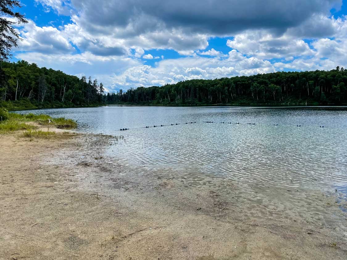 sandy beach under a cloudy sky at the day-use area of Esker Lakes Provincial Park