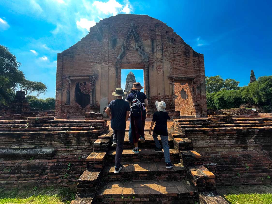 A woman and two children walking up steps towards a tower in Wat Ratchaburana in Ayutthaya, Thailand