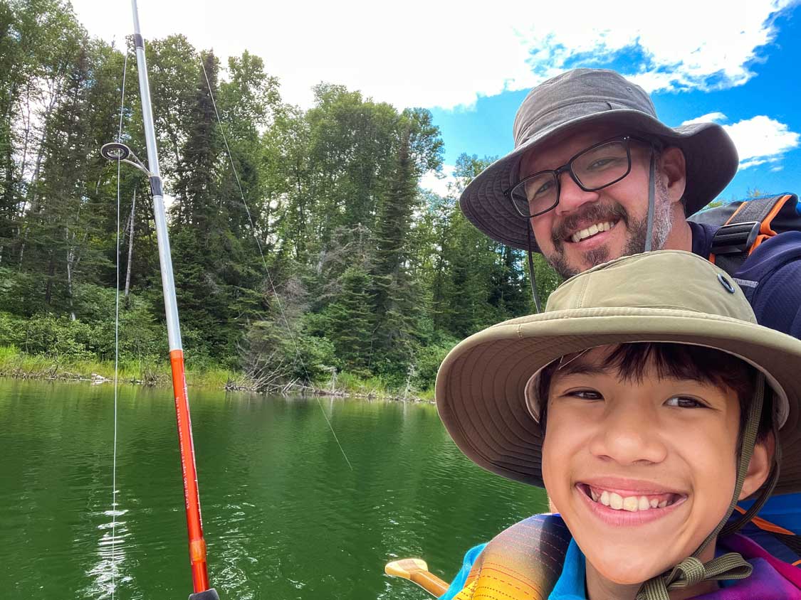 Father and son smiling at the camera while fishing in Esker Lakes Provincial Park