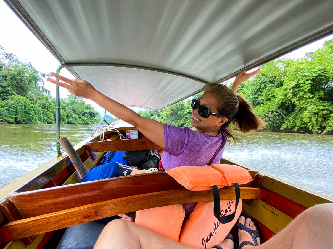 Woman waves while riding a longtail boat on the Kwai River
