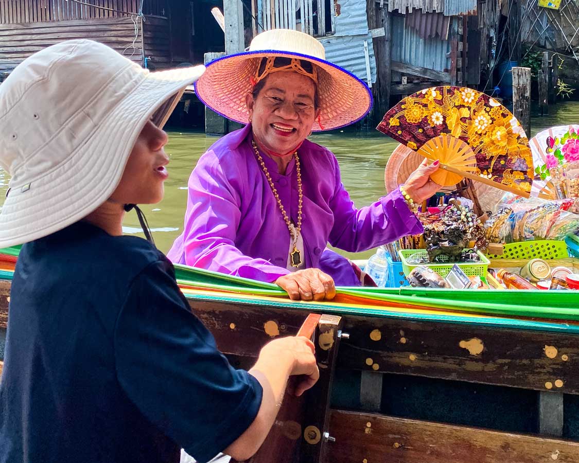 Boy talking to a vendor at the Bangkok floating markets