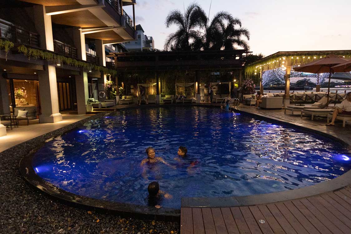 family swimming at sunset at Riva Surya in Bangkok