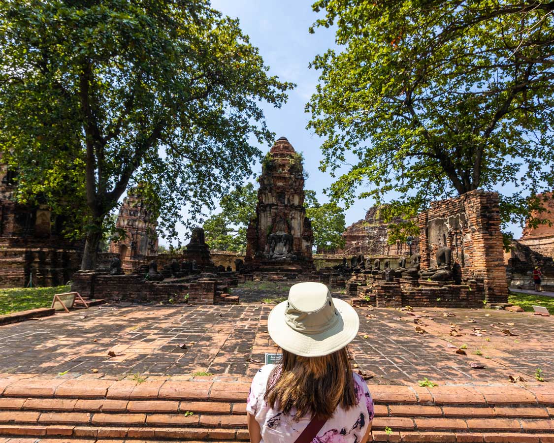 Woman looking at a temple in Wat Mahathat, one of the coolest places to visit in Ayutthaya, Thailand
