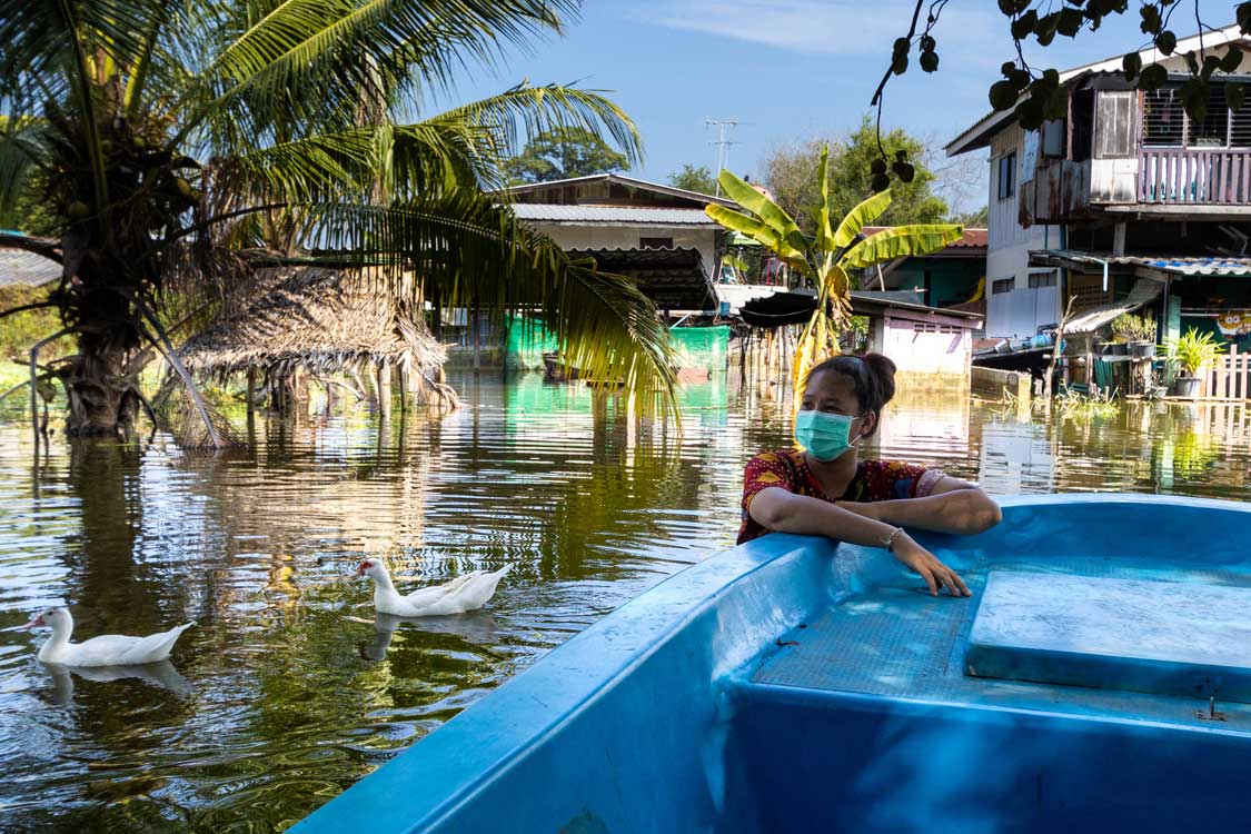 Woman pushing tourists through flooded neighborhood in Ayutthaya, Thailand