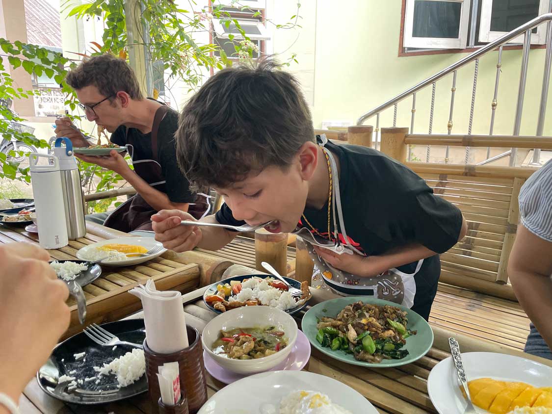 A boy eats Thai food at a cooking class in Phuket, Thailand