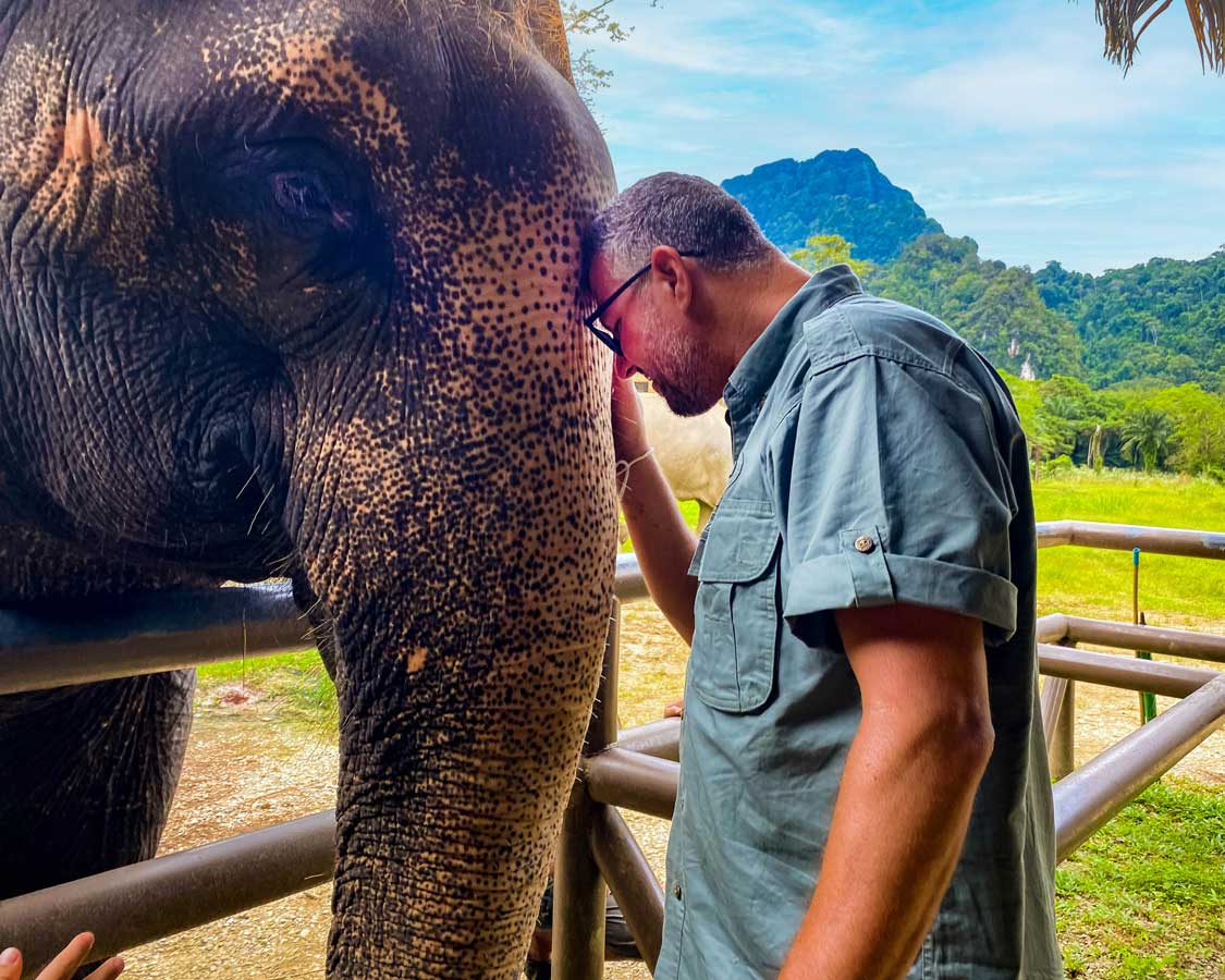 A man rests his head on an elephant's trunk at the Elephant Hills sanctuary in Thailand