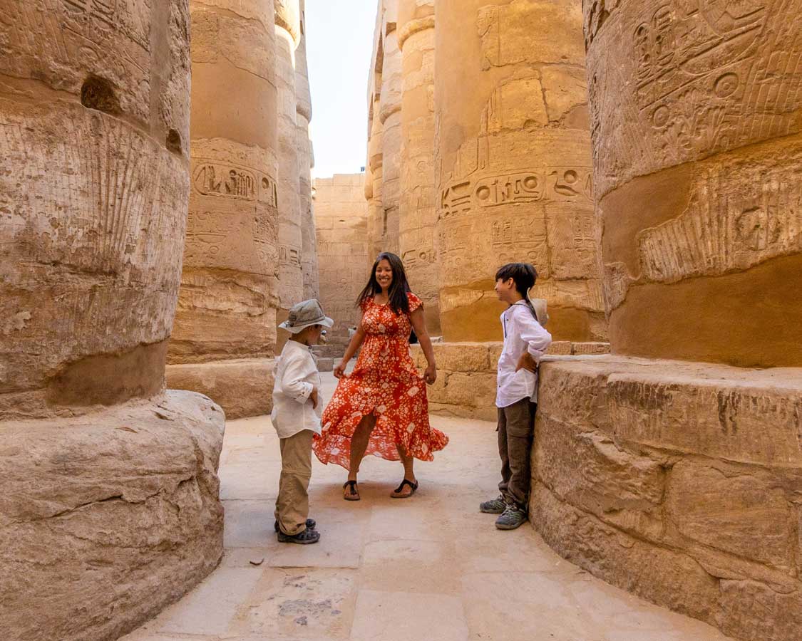 A woman staying healthy while traveling by dancing among columns in Luxor Egypt