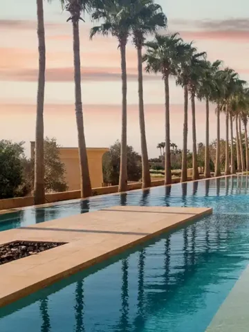 A father walks with his on through a palm-lined pool at the Kempinski Hotel Ishtar Dead Sea in Jordan