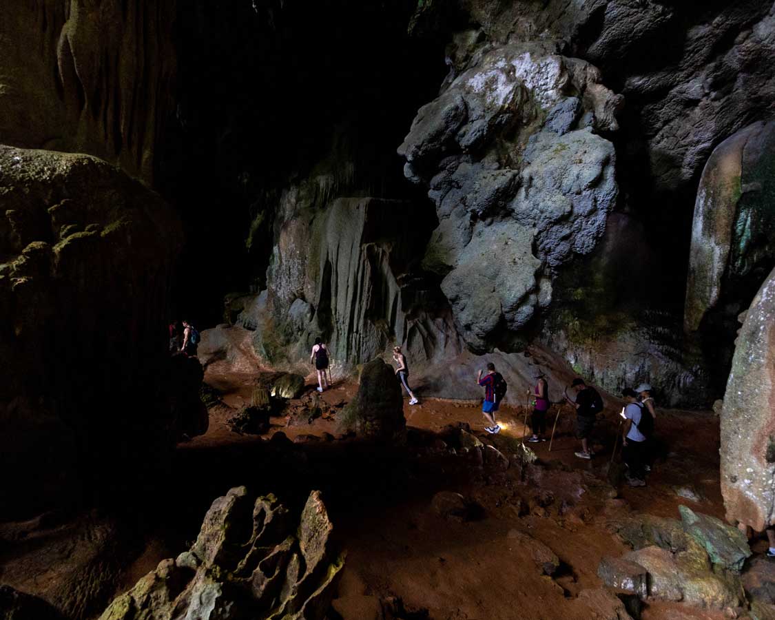 Hikers trek through a mountain cave in Khao Sok National Park