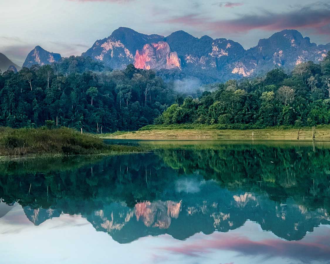 Sunset over limestone mountains and a clear lake in Khao Sok National Park