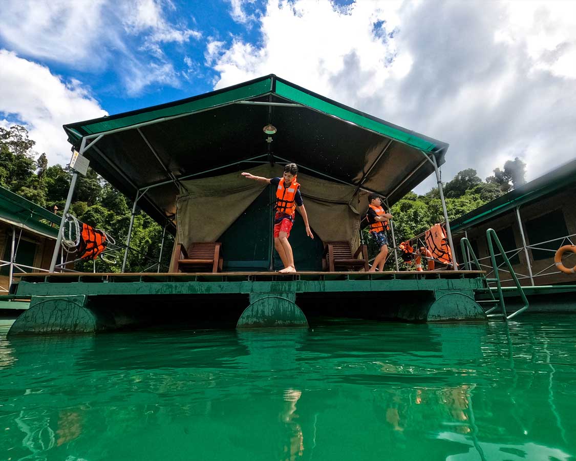 A boy jumps from a floating lodge into Cheow Lan Lake at Elephant Hills Rainforest Floating Lodge