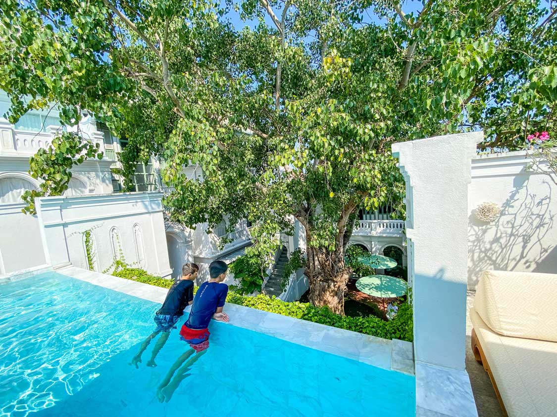 Two boys sitting in a pool looking out over the courtyard of a beautiful hotel