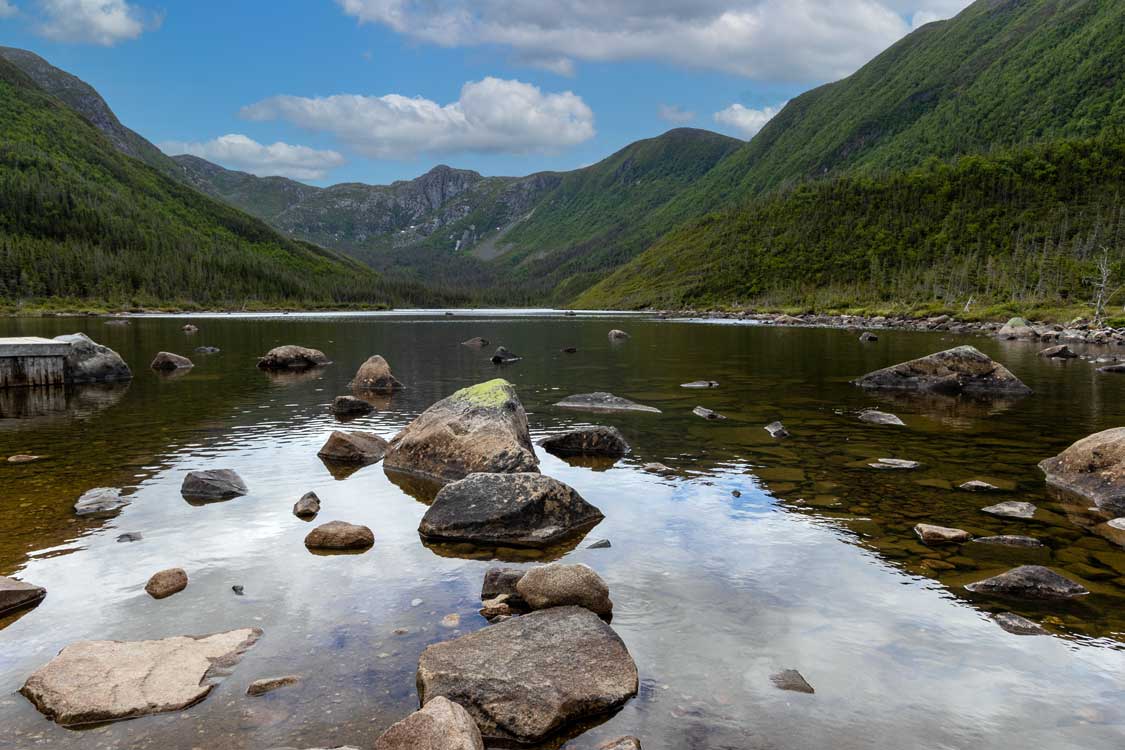 A shallow crystal-clear lake sits amidst mountains in Gaspesie National Park Quebec