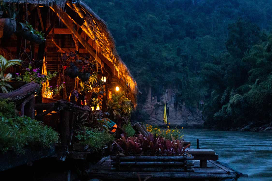 A floating hotel on the River Kwai lit with kerosene lanterns