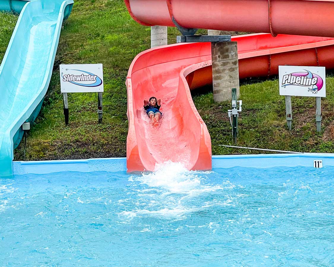 A boy slides down a red waterslide at Magic Mountain Splash Zone