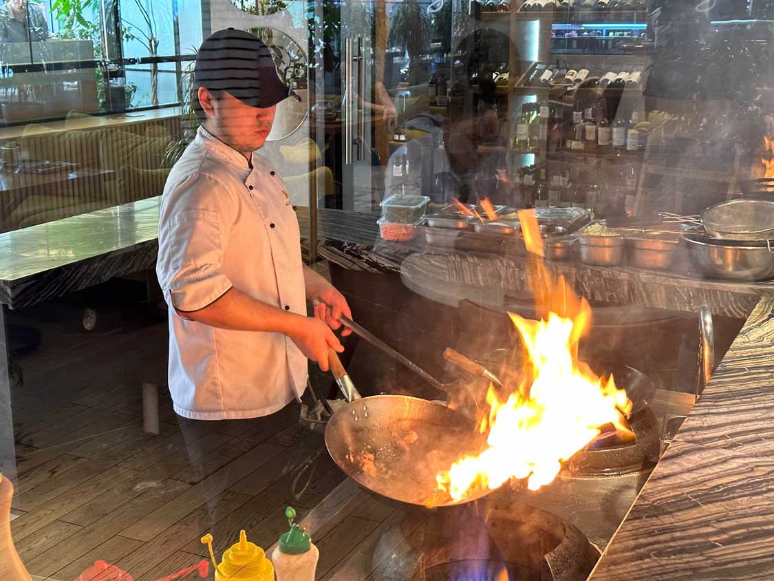 A chef swirls a flaming pot at The Noodles restaurant in Almaty