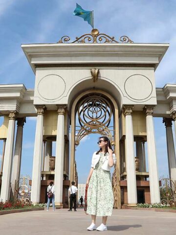 Woman standing in front of an artch at First President's Park - one of the best things to do in Almaty, Kazakhstan