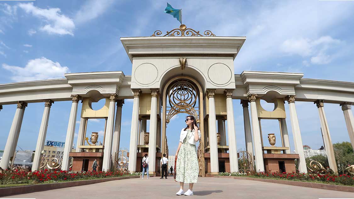 Woman standing in front of an artch at First President's Park - one of the best things to do in Almaty, Kazakhstan