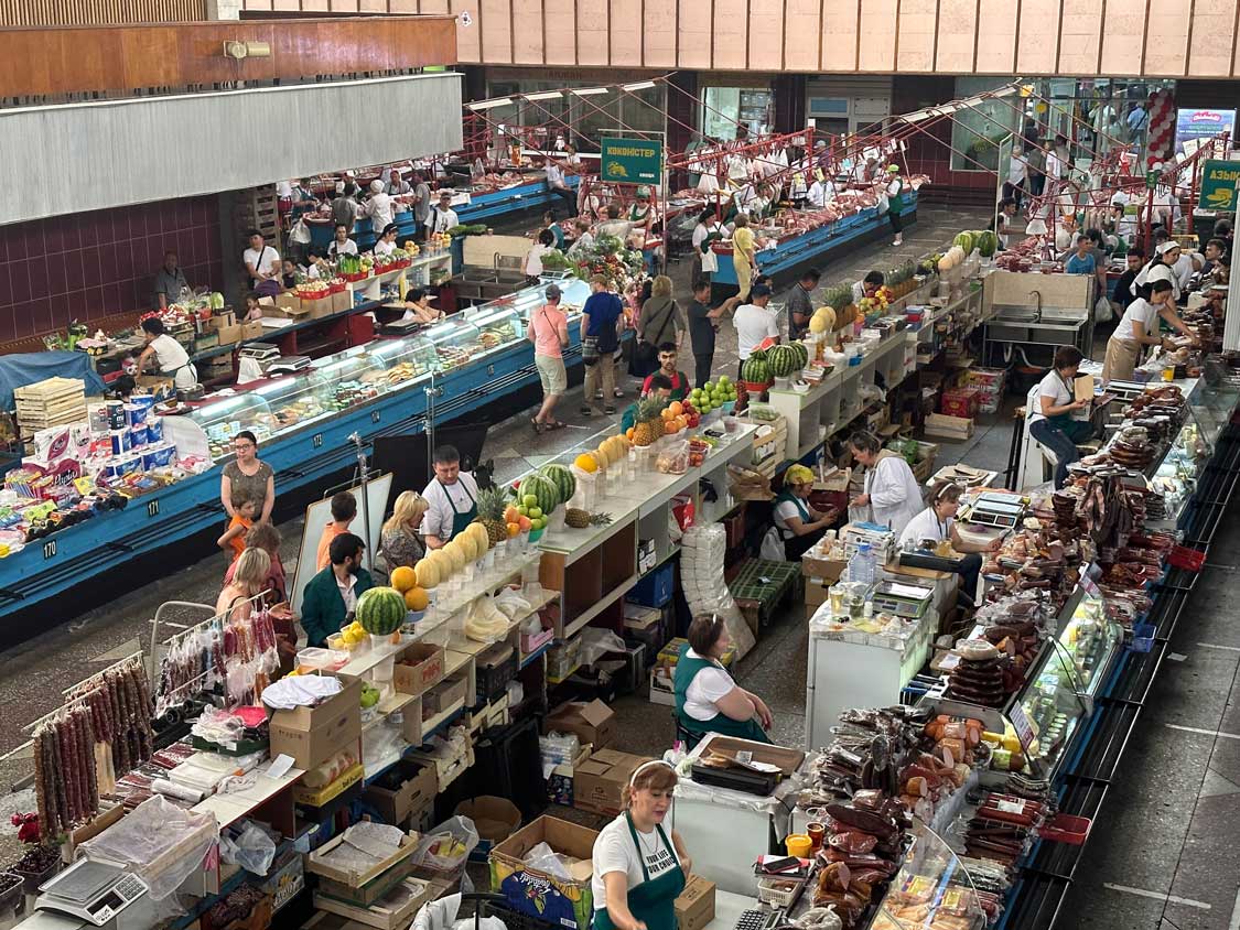 Vendors line aisles selling meat and fruit at the Green Bazaar in Almaty Kazakhstan