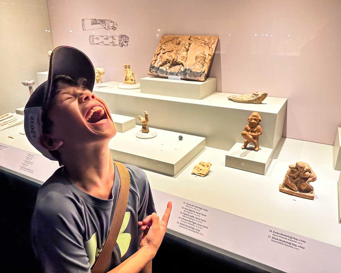 A young boy laughs at a statue at the Ephesus Archaeological Museum in Selcuk, Turkiye