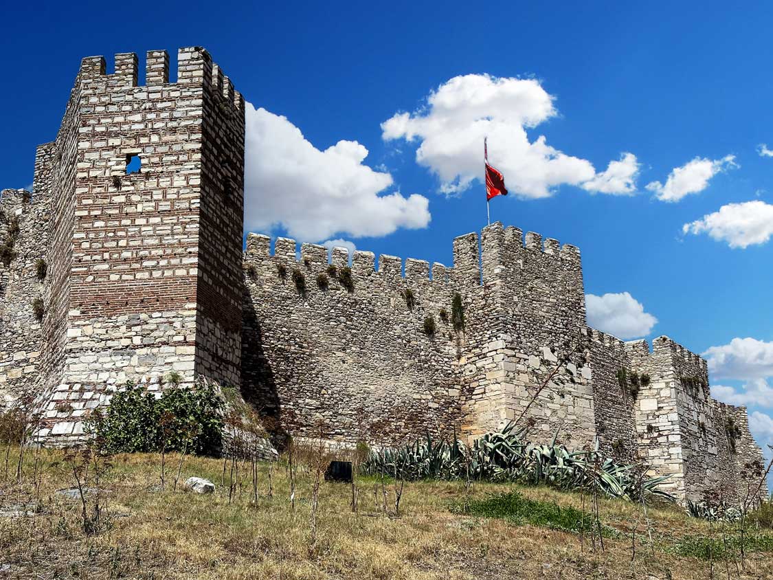 A towering castle wall with a battlement flying a Turkish Flag at the Ayasuluk Castle in Selcuk