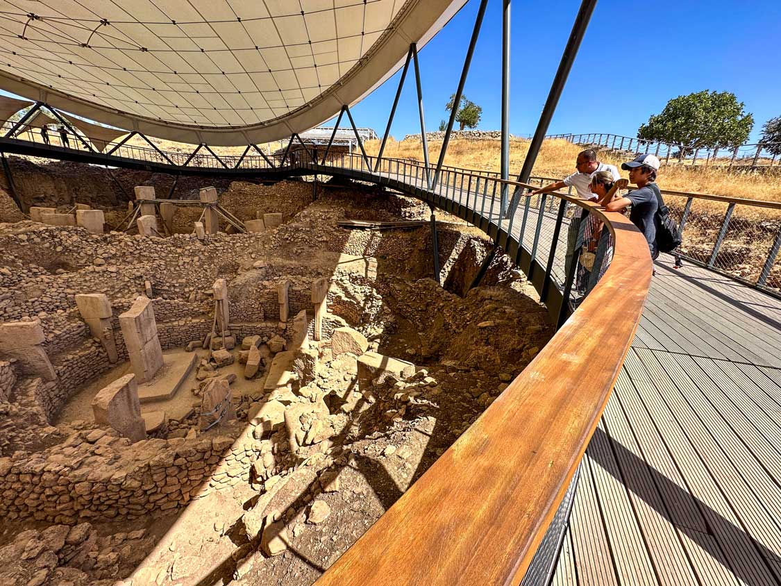 A family looks into an archaeological site containing the oldest human structure in the world at Gobleki Tepe, Turkiye