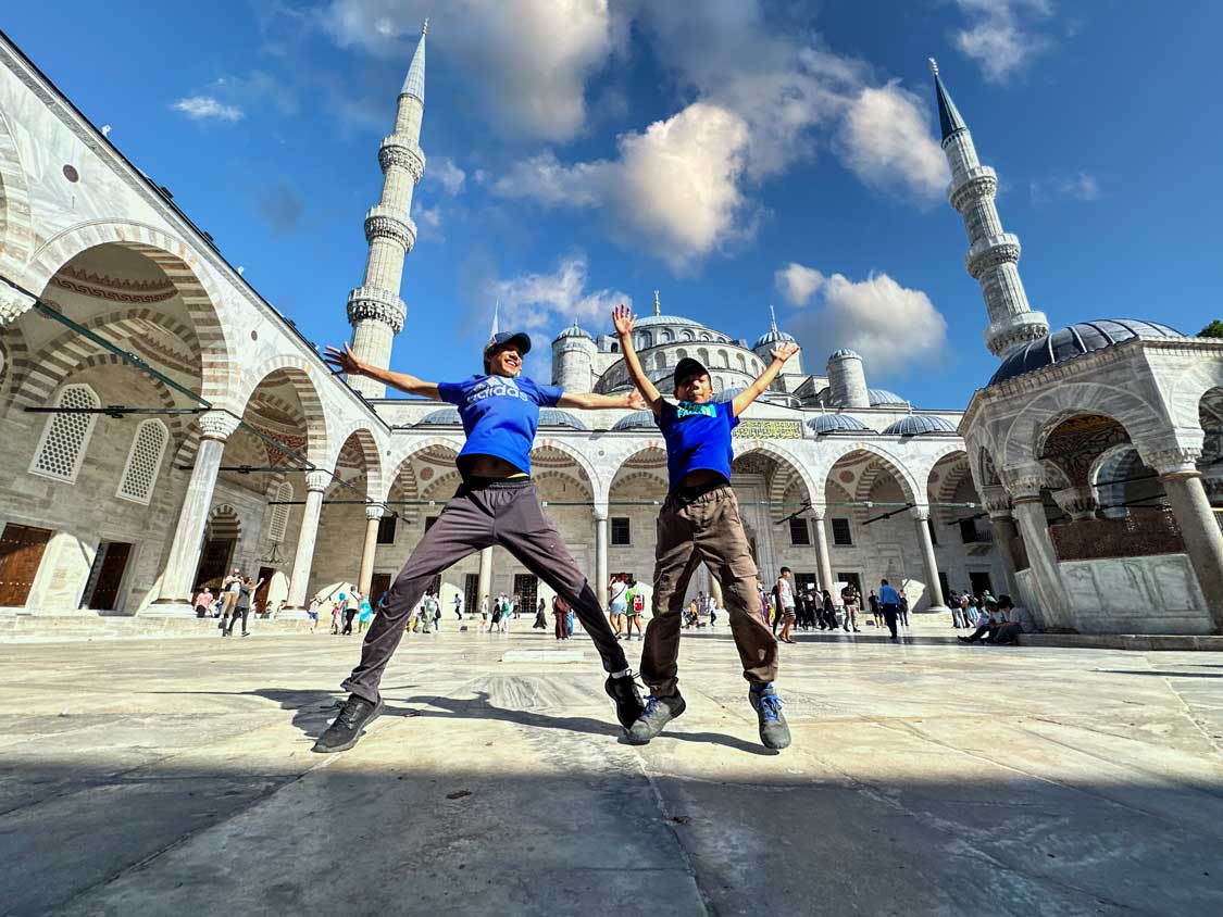 Smiling boys jumping in front of the Blue Mosque in Istanbul