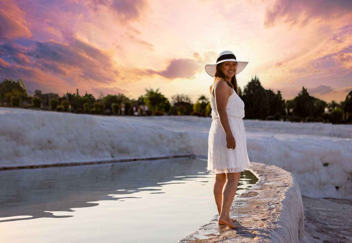 Woman walking along the rim of a white geothermal pool at Pamukkale, Turkiye