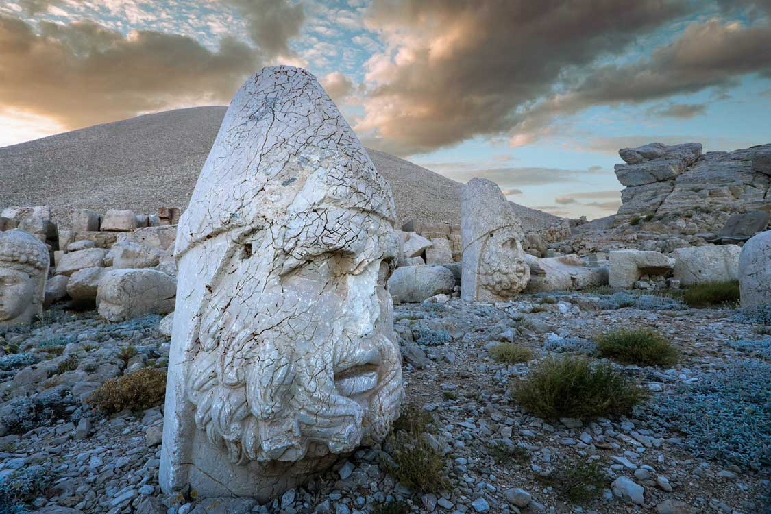 The stone head from a sculpture of Antiochus I sits on a mountaintop beneath a beautiful sunrise on Mount Nemrut