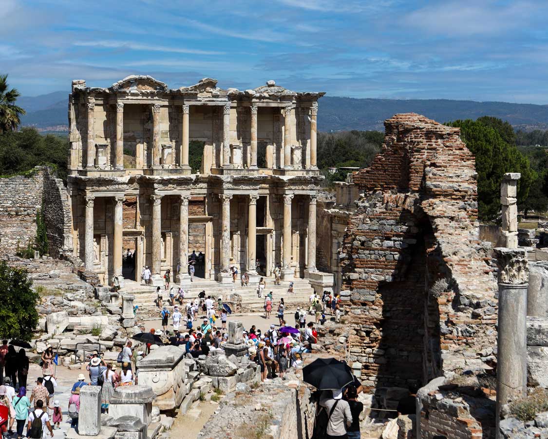 A crowd forms around a stunning Roman ruin known as the Library of Celsus