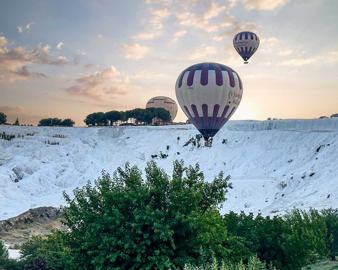 Hot air balloons at sunrise of the calcite pools of Pammukale