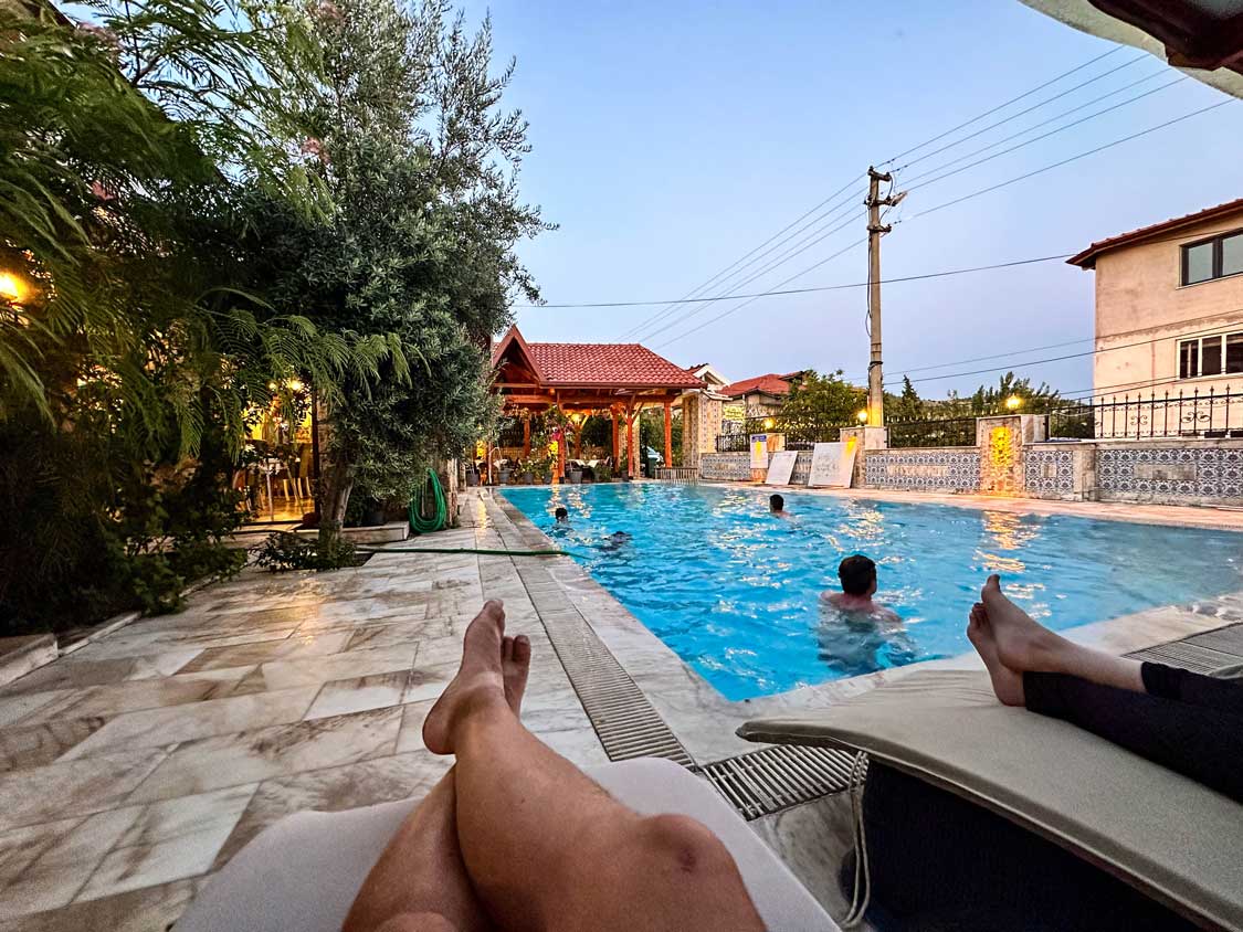 Legs of a man sitting by a pool at a hotel in Pamukkale while he watches his children swim in the pool