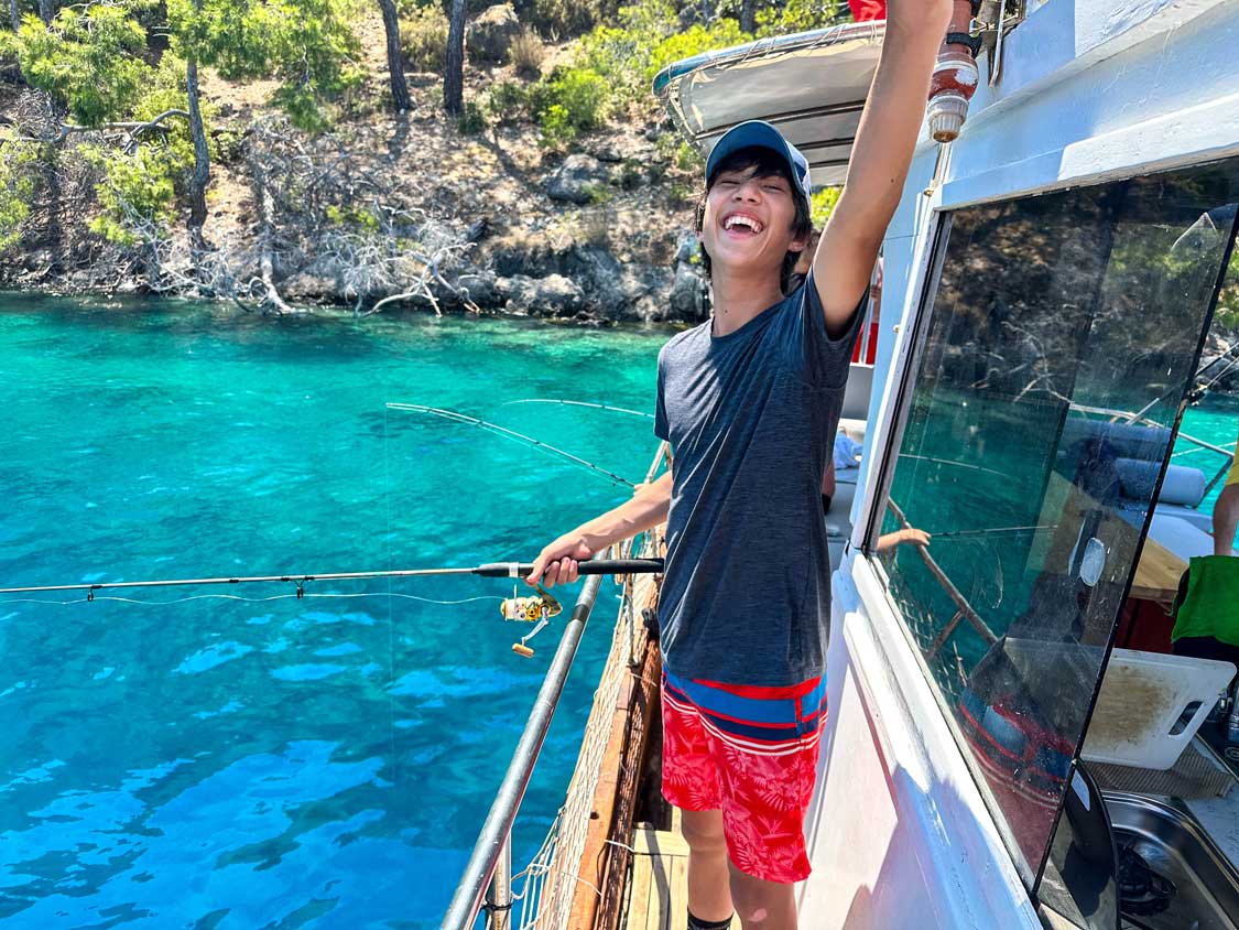 A teen boy smiles while fishing in Fethiye, Turkiye