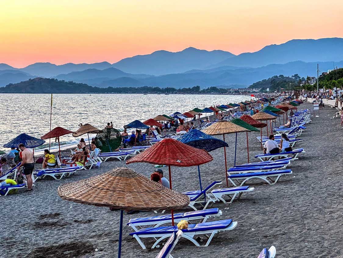 Sunset over Calis Beach in Fethiye Turkiye with lines of umbrellas and sunchairs