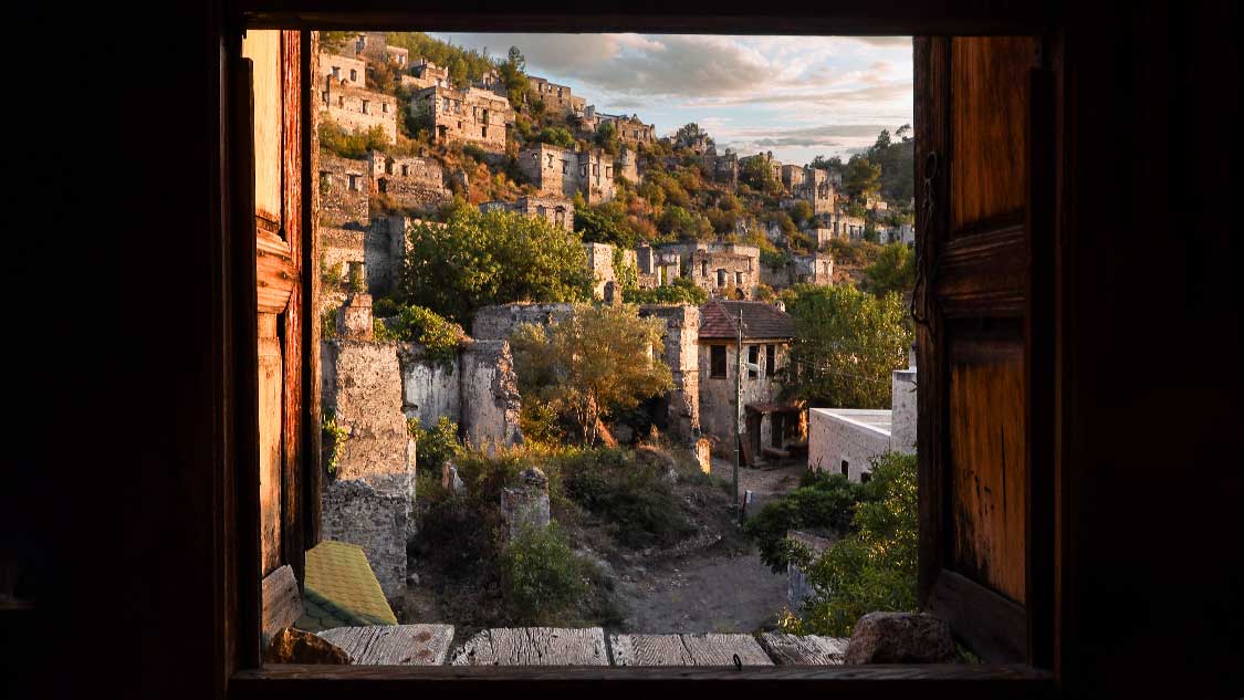 The Turkish ghost town of Kayakoy viewed through the window of an abandoned house