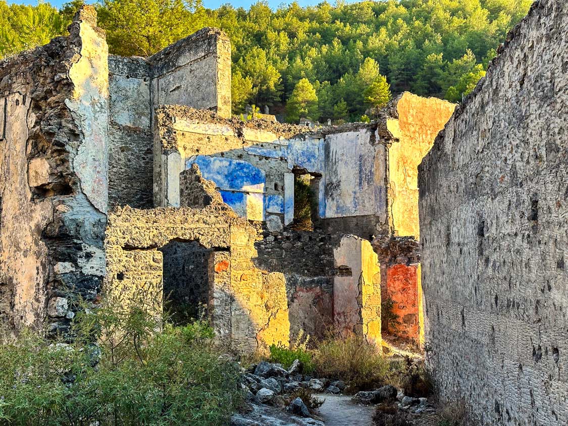 Crumbling ruins of houses, some with brightly painted walls, in Kayakoy abandoned village