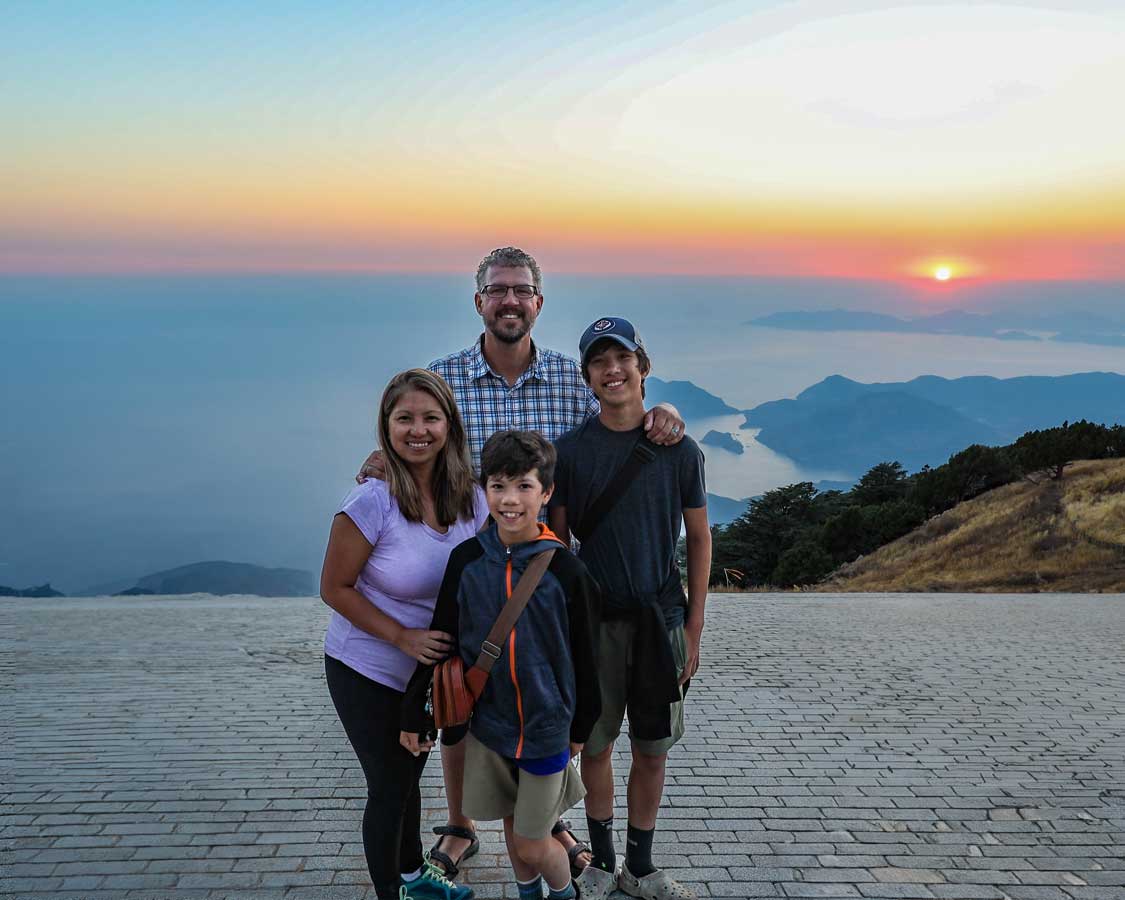 The Wandering Wagars family smiling for a photo on top of Mount Babadag at sunset
