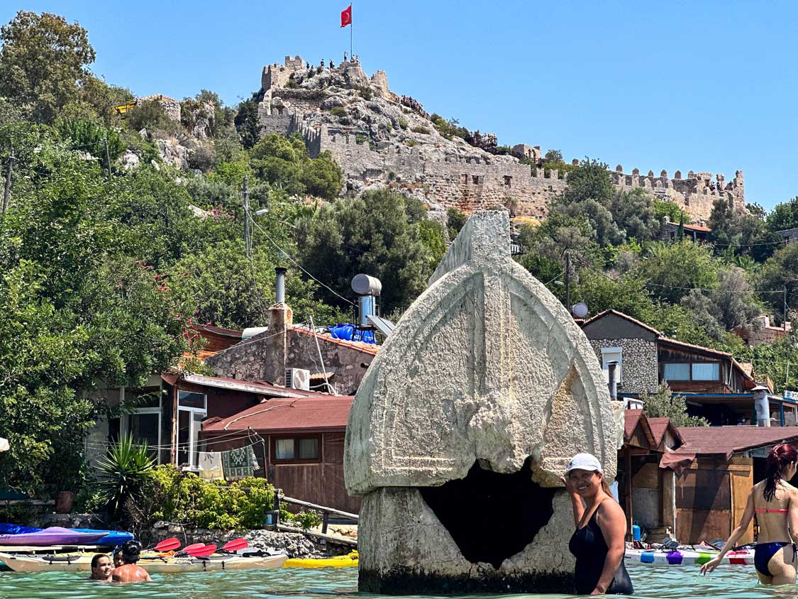 Christina stands in the water at Kekova Island in front of Simena Castle