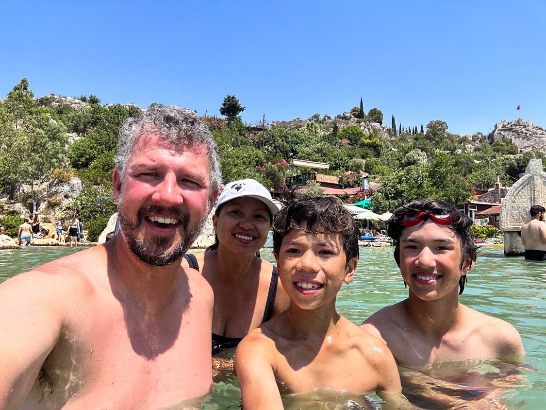 The Wandering Wagars smile for a selfie in front of Simena Castle in Demre, Turkiye