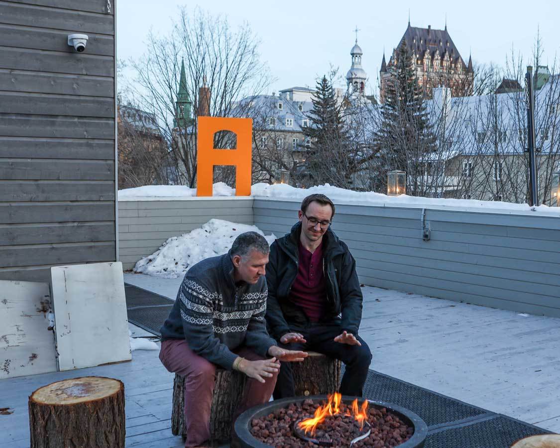 Two men enjoy a firepit on the rooftop terrace of Hotel AtypiQ
