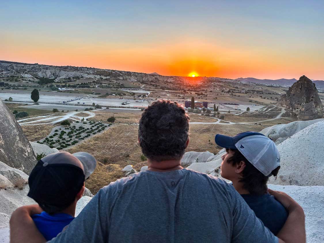A man and his children watch the sunset from Red Valley in Cappadocia