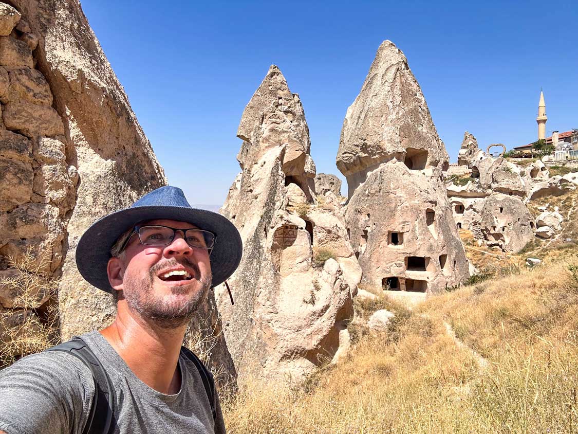 A man wearing a blue hat hikes through the valleys of Cappadocia