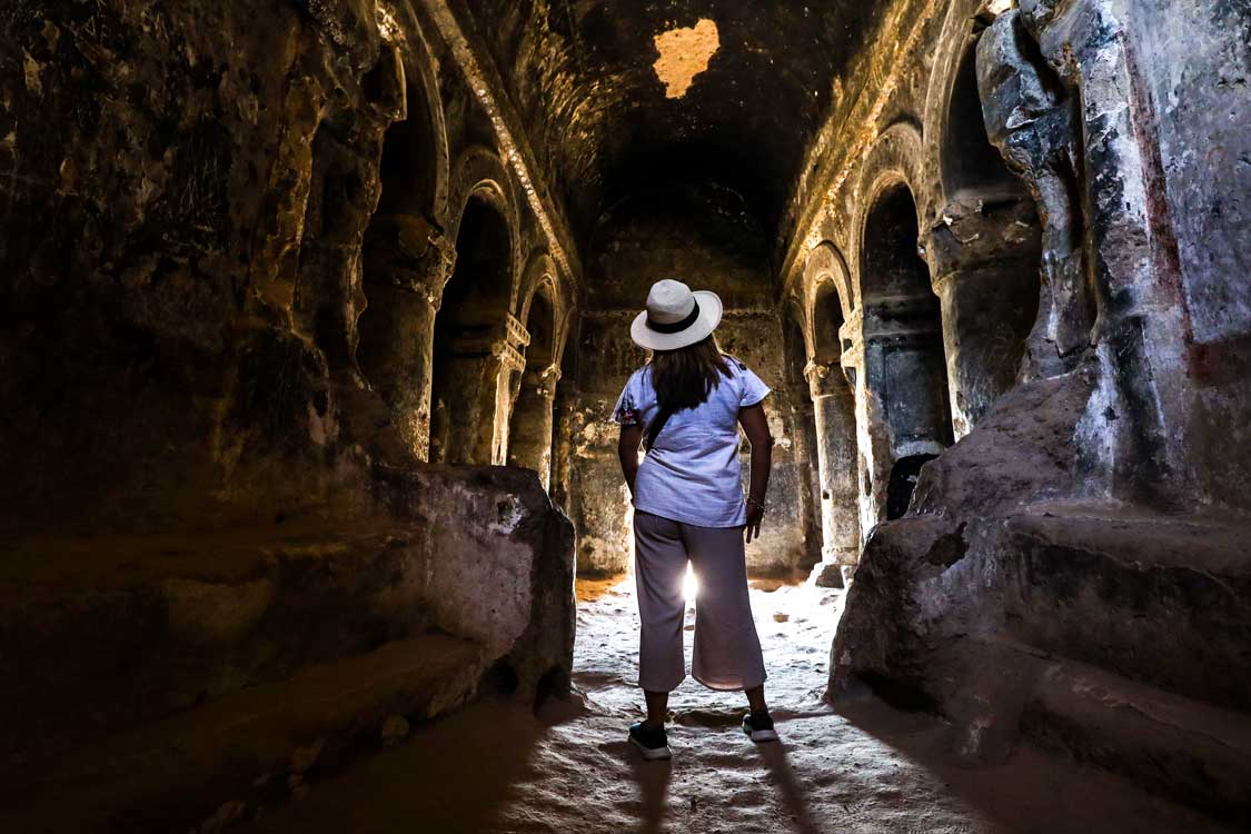 A woman explores an intricate cave church at the Selime Cathedral in Cappadocia