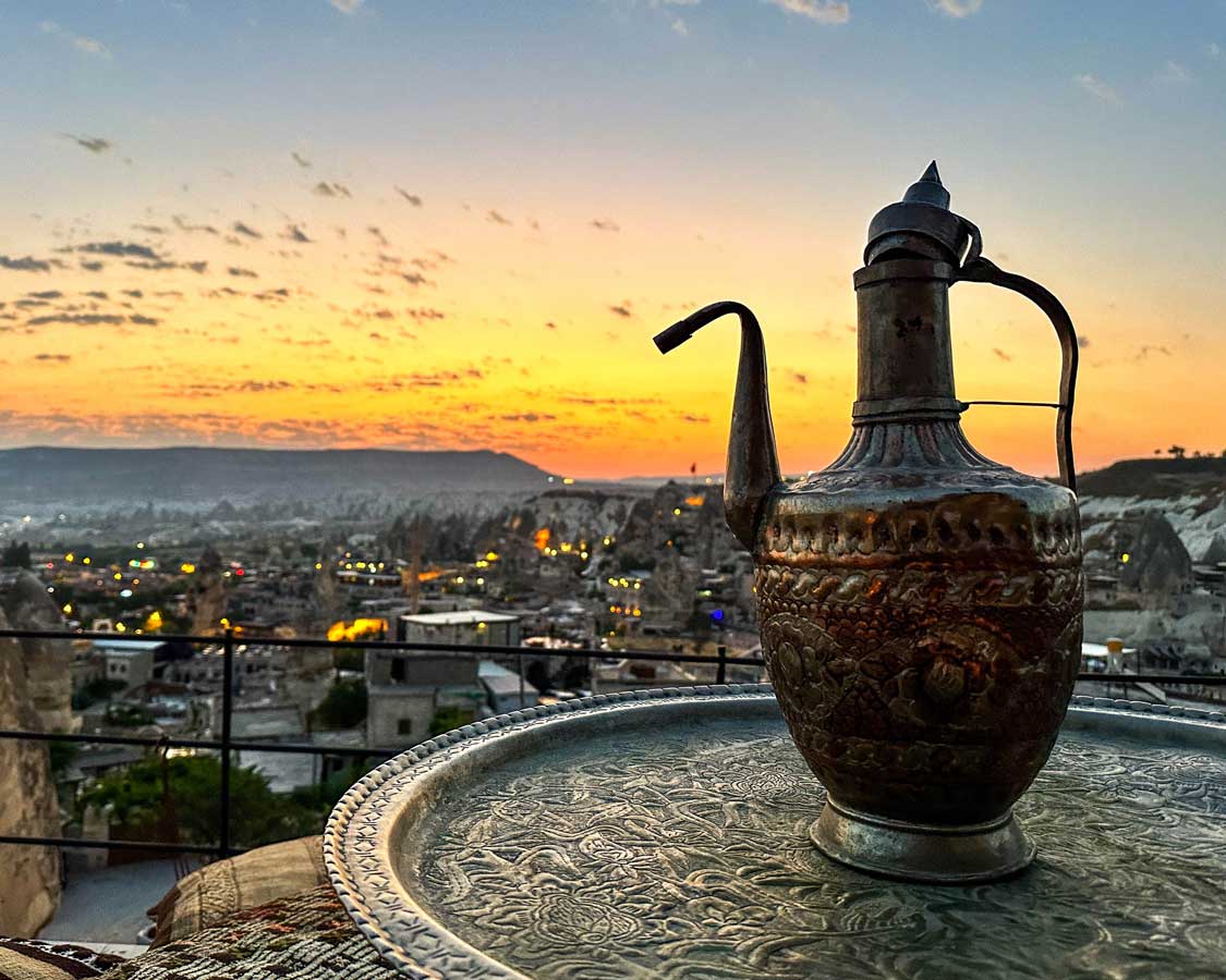 An intricate Turkish teapot rests on a metal table during sunset in Cappadocia