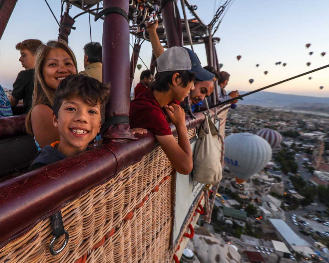 A family looks out from a hot air balloon in Goreme, Turkiye