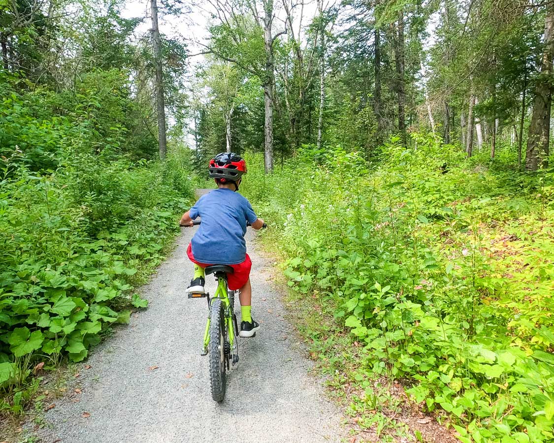 A boy bikes through the forest at Parc National de Plaisance in Montebello, Quebec