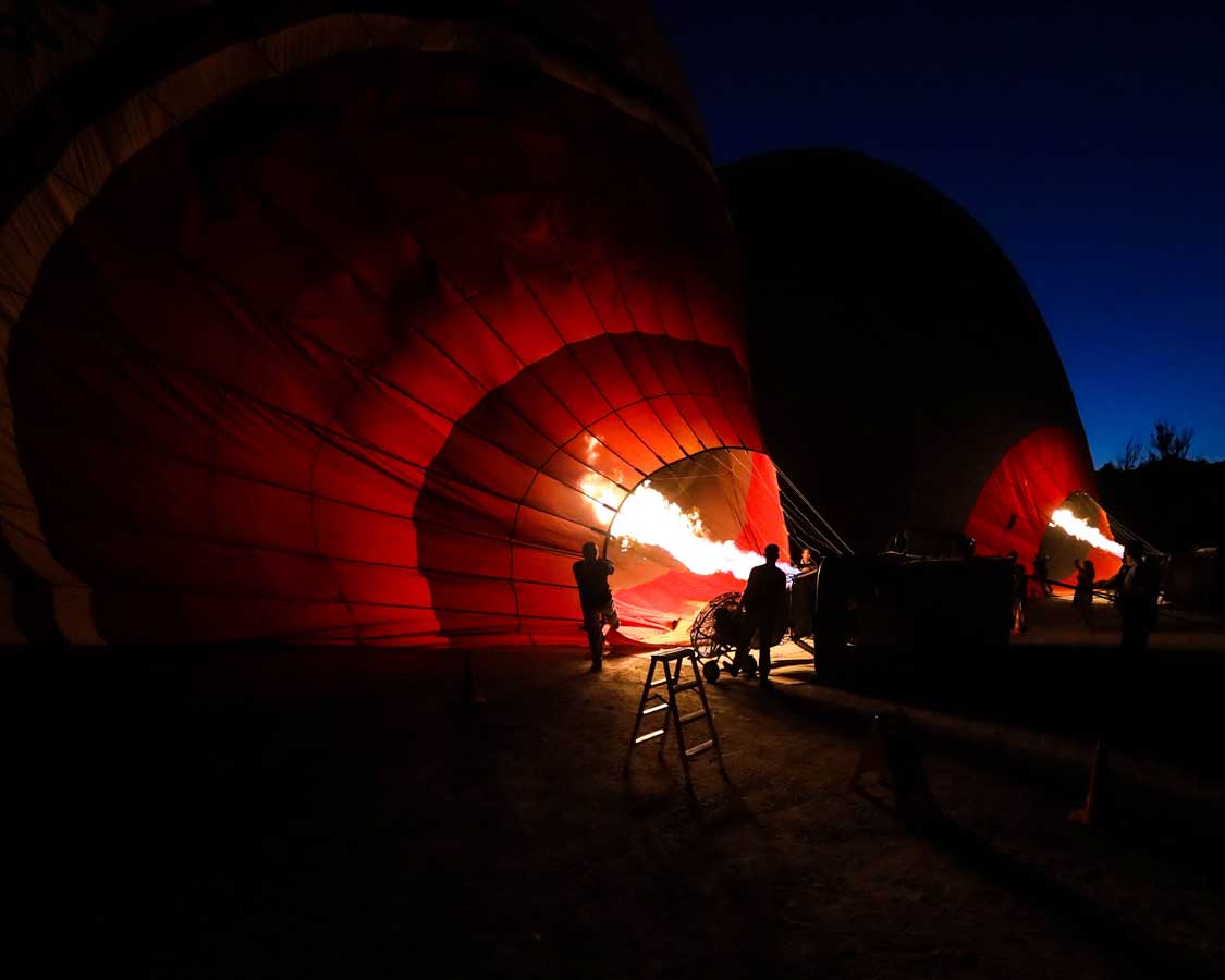 Fire casts a silhouette of a hot air balloon crew in Cappadocia