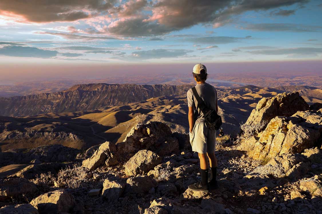 A boy watches the sunrise from Mount Nemrut