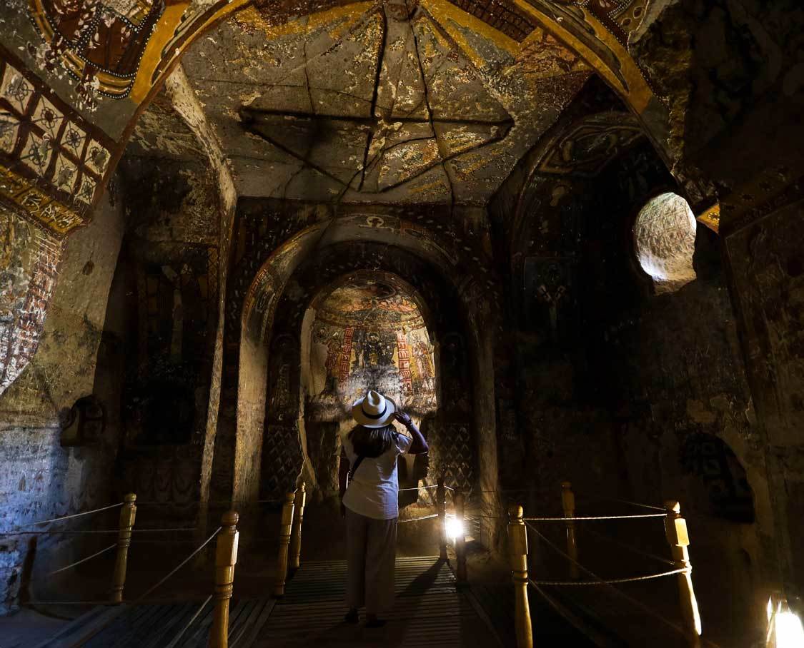 A woman looks up at church frescoes in a cave church in the Ihlara Valley in Cappadocia