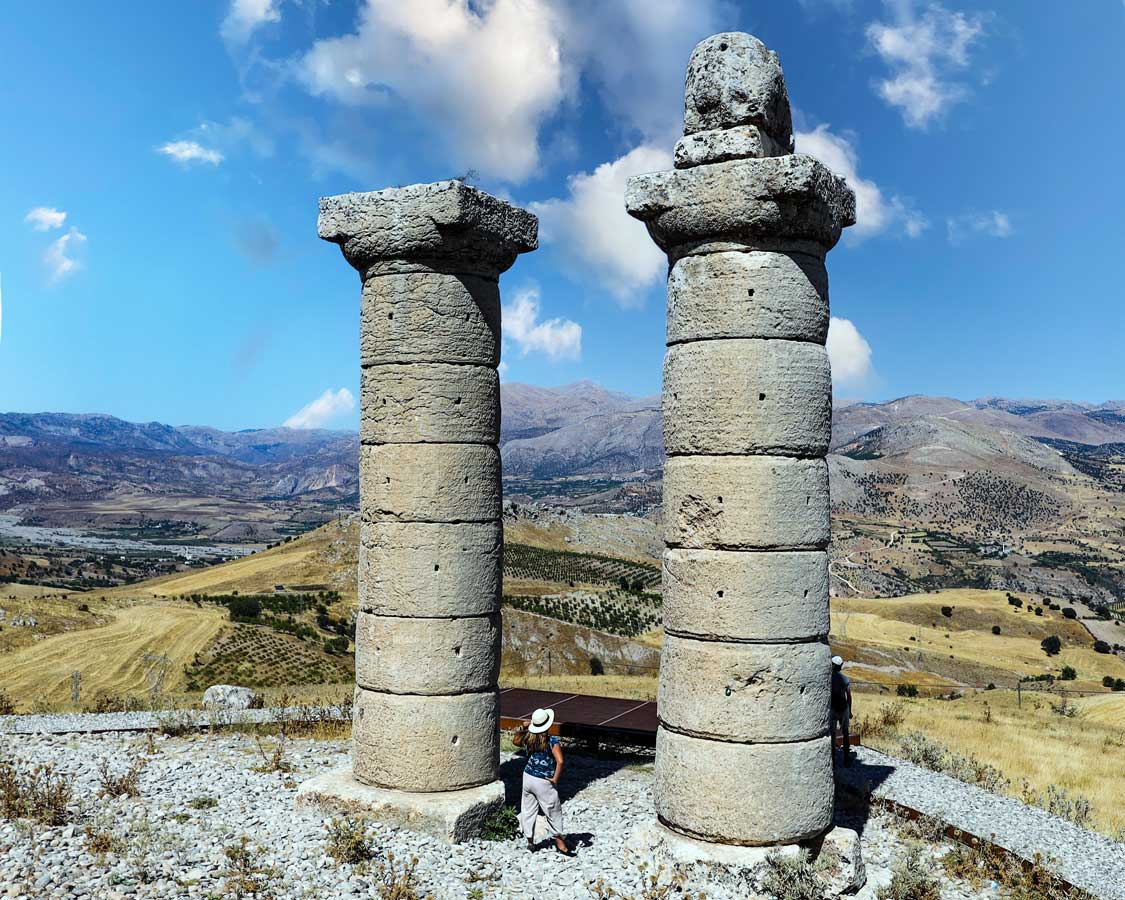 A woman looks up between two large pillars at Karakus Tumulus near Sanliurfa, Turkiye